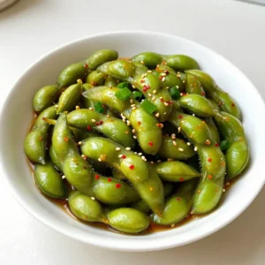 To make spicy garlic edamame, you will need: - 2 cups edamame pods (fresh or frozen) - 4 cloves garlic, finely minced - 2 tablespoons extra virgin olive oil - 1 tablespoon low-sodium soy sauce - 1 teaspoon crushed red pepper flakes - 1 tablespoon sesame seeds (toasted, for extra flavor) - Salt, to taste - 1 tablespoon finely chopped green onions (for garnish) I recommend using frozen edamame for this recipe. It is easy to find and cooks quickly. Frozen edamame is picked at peak freshness, so the taste is great. Fresh edamame works too. If you choose fresh, look for bright green pods that feel firm. If you want to change things up, here are some easy swaps: - Use garlic powder instead of fresh garlic in a pinch. - Swap olive oil for sesame oil for a richer flavor. - You can try tamari instead of soy sauce for a gluten-free option. - If you don't have sesame seeds, you can use chopped nuts for crunch. {{ingredient_image_2}} Start by cooking the edamame pods. If you use frozen edamame, fill a pot with water. Bring the water to a boil. Add the edamame pods and cook them for about 5 minutes. They should be tender. After cooking, drain the pods well and set them aside. Next, heat a medium skillet on medium heat. Pour in 2 tablespoons of extra virgin olive oil. Let it warm up. Add 4 finely minced garlic cloves to the skillet. Stir the garlic for 1-2 minutes. You want it to smell nice and fragrant. Be careful not to let it burn. Burnt garlic tastes bad. Now, add the cooked edamame to your skillet. Pour in 1 tablespoon of low-sodium soy sauce and 1 teaspoon of crushed red pepper flakes. Sprinkle in a little salt for taste. Stir everything well to coat the edamame in that garlic goodness. Cook for another 2-3 minutes. Stir often, so everything heats evenly. Once heated, take the skillet off the heat. Sprinkle 1 tablespoon of toasted sesame seeds on top. Add 1 tablespoon of finely chopped green onions for color and crunch. Serve the spicy garlic edamame warm. You can use a rustic bowl for a nice touch. Enjoy this flavor-packed snack! To cook edamame well, start with fresh or quality frozen pods. Boil them until tender, usually around five minutes. Drain the pods well to keep them from being soggy. If you want a bit more flavor, try using vegetable broth instead of water. This adds depth without extra effort. Adjusting spice is easy. Start with a small amount of crushed red pepper flakes. You can always add more later. If you want less heat, reduce the flakes or skip them. For extra heat, add more. Another option is to drizzle a bit of sriracha or chili oil before serving. For a beautiful presentation, use a rustic bowl for the edamame. Sprinkle the toasted sesame seeds and green onions on top for color. You can also serve them in a platter with your favorite dipping sauces. This makes them fun for sharing. Always serve the edamame warm for the best taste experience. Pro Tips Choose Fresh Edamame: Fresh edamame pods will give you a better texture and flavor compared to frozen. Look for bright green pods without blemishes. Control the Heat: Adjust the amount of crushed red pepper flakes to suit your spice preference. Start with less and add more gradually if desired. Perfect Garlic Saut&eacute;: Be vigilant while saut&eacute;ing garlic; it can quickly turn from fragrant to burnt. Remove it from the heat as soon as it becomes golden. Garnish for Flavor: Don&rsquo;t skip the toasted sesame seeds and green onions; they add a delightful crunch and enhance the overall flavor of the dish. {{image_4}} You can easily make spicy garlic edamame vegan. The recipe is naturally vegan since it uses edamame and garlic. For a gluten-free version, use tamari instead of soy sauce. Tamari has a similar taste but is free of gluten. This way, everyone can enjoy the dish without worry. You can add more flavor to your edamame. Try adding a splash of lime juice for a zesty twist. Another option is mixing in some ginger for a spicy kick. You may also add a dash of sesame oil for a nutty flavor. For an Asian touch, consider adding chopped cilantro. These simple changes can take your snack to the next level. Spicy garlic edamame is great for many events. Serve it as an appetizer at parties and gatherings. It also works well as a side dish for Asian meals. If you have friends over, serve it with drinks for a fun snack. For movie nights, present it in a bowl for easy sharing. The vibrant colors and bold flavors make it a hit every time! To store leftover spicy garlic edamame, place it in an airtight container. Be sure to cool it to room temperature before sealing. This helps keep the flavors fresh. You can store it in the fridge for up to three days. If you have more leftovers, consider freezing them for later use. To reheat the edamame, you can use a skillet or microwave. For the skillet, heat it over medium-low heat. Add the edamame and a splash of water. Stir until warmed through, about 5 minutes. If using a microwave, place the edamame in a microwave-safe bowl. Cover it with a damp paper towel and heat for about 1-2 minutes. When stored properly, spicy garlic edamame lasts up to three days in the fridge. If frozen, it can last for about three months. Just remember to thaw it overnight in the fridge before reheating. Always check for off smells or changes in texture before eating leftovers. Enjoy your flavorful snack! The best way to cook edamame is to boil it. Start with fresh or frozen edamame pods. If using frozen, add them to boiling water. Cook for about 5 minutes until tender. Drain the pods well before using them in your recipe. This method keeps the beans bright green and tasty. Yes, you can make Spicy Garlic Edamame in advance. Prepare it and let it cool completely. Store it in an airtight container in the fridge. It will last for up to three days. When you're ready to eat, reheat it in a skillet over medium heat until warmed through. To make this recipe less spicy, reduce the amount of crushed red pepper flakes. You can start with half a teaspoon. If you want even less heat, skip the red pepper altogether. The garlic and soy sauce will still give you great flavor. Yes, edamame is very healthy! It is high in protein, fiber, and vitamins. Edamame is also low in calories and fat. It can support heart health and aid digestion. Eating edamame can be a great addition to your diet. This blog covered how to make spicy garlic edamame. You learned about key ingredients, step-by-step instructions, and tips for success. I also shared variations and storage ideas to keep your dish fresh. Remember, edamame is not just tasty; it's healthy too. Feel free to tweak flavors and serve it anytime. Cooking can be fun, and this recipe is a great way to start. Enjoy making your own delicious version!