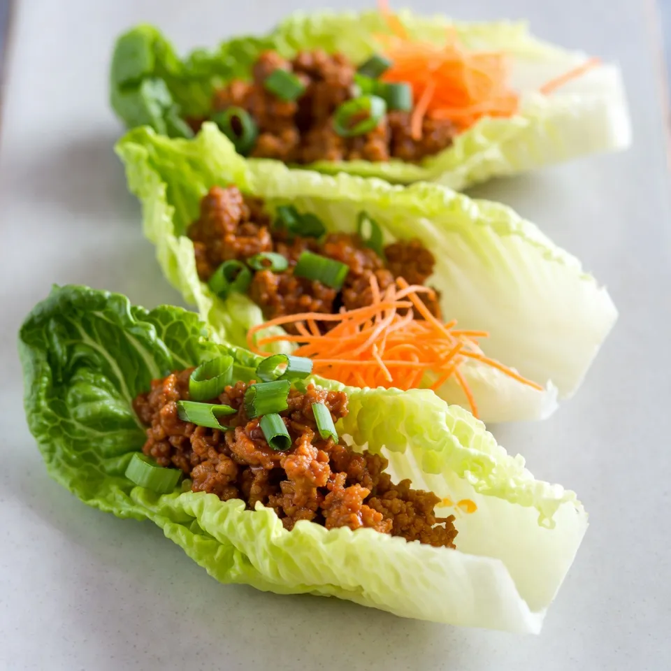 - 1 lb ground chicken - 1/3 cup buffalo sauce (mild or hot) - 1 tablespoon olive oil - 2 cloves garlic, minced - 1/2 teaspoon onion powder - 1/2 teaspoon smoked paprika - Lettuce leaves (romaine or butter) The main ingredients give your wraps a great taste. Ground chicken is lean and easy to cook. Buffalo sauce adds heat and flavor. Olive oil helps to sauté the garlic and chicken. Garlic brings a strong aroma. Onion powder and smoked paprika add depth to the dish. The lettuce serves as a fresh, crunchy wrap. - Blue cheese or ranch dressing - Green onions, sliced - Shredded carrots These optional ingredients let you customize your wraps. Blue cheese or ranch dressing adds creaminess. Green onions provide a fresh crunch. Shredded carrots add color and sweetness. Use these extras to enhance the taste and presentation. - Turkey or tofu instead of chicken - Homemade buffalo sauce You can easily swap the chicken for turkey or tofu. This makes the dish suitable for different diets. If you want to control the heat, try making your own buffalo sauce. This way, you can adjust the flavors to your liking. {{ingredient_image_2}} 1. Start by heating a large skillet over medium heat. Add 1 tablespoon of extra virgin olive oil. 2. Once the oil is hot, add 2 cloves of minced garlic. Sauté for about 1 minute. You want it fragrant, not browned. 3. Next, add 1 pound of ground chicken to the skillet. Use a wooden spoon to break it apart. Cook for 5 to 7 minutes until it’s browned and no longer pink. Stir occasionally for even cooking. 4. Now, sprinkle in 1/2 teaspoon of onion powder and 1/2 teaspoon of smoked paprika. Add a pinch of salt and black pepper. Stir well to coat the chicken with the spices. 1. Gradually pour in 1/3 cup of buffalo sauce. Mix it in thoroughly with the chicken. 2. Let the mixture simmer for 2 to 3 minutes. This helps to blend the flavors and heat everything through. 1. Select a head of romaine or butter lettuce. Gently separate the leaves and rinse them. 2. Take a leaf and spoon about 2 to 3 tablespoons of the buffalo chicken mixture into the center. 3. To finish, add a sprinkle of 1/4 cup of sliced green onions and 1/4 cup of shredded carrots on top. If you like, drizzle some blue cheese or ranch dressing over it for extra flavor. Now, fold the sides of the lettuce leaf over the filling and enjoy these tasty bites! To get a nice, even browning on your chicken, use medium heat. This helps the meat cook through without burning. Make sure to break the chicken into small pieces while it cooks. This ensures each bite is tasty and well-seasoned. Adjusting spice levels is simple. If you want it milder, use less buffalo sauce. A mild buffalo sauce can still pack flavor without too much heat. For those who love spice, go for the hot version. You can also add cayenne pepper to kick it up a notch. For a great presentation, serve the wraps on a big platter. Arrange the lettuce wraps neatly. Add extra shredded carrots and green onions around the edges. This makes the dish look colorful and inviting. Consider serving blue cheese or ranch dressing on the side. This creamy touch adds a rich flavor contrast. You can also pair these wraps with a fresh salad or crunchy veggie sticks for a full meal. To store leftovers, place the chicken mixture in an airtight container. Keep it in the fridge for up to three days. Make sure to store the lettuce leaves separately. This keeps them crisp and fresh. When you're ready to eat, reheat the chicken mixture in a skillet. Heat it on low until warm. Avoid high heat to keep the chicken juicy. You can also use the microwave, but stir it every 30 seconds for even warming. Pro Tips Choose Your Heat Level: Select a buffalo sauce that matches your preferred spice level; milder sauces are great for those who enjoy less heat, while hotter options will satisfy the spice lovers. Fresh Herbs for Extra Flavor: Consider adding fresh herbs like cilantro or parsley to the wraps for an additional layer of flavor and freshness. Make Ahead: Prepare the buffalo chicken mixture in advance and store it in the refrigerator. This makes for a quick assembly when you're ready to eat! Experiment with Dressings: While blue cheese and ranch dressings are classic choices, try experimenting with other dressings like a spicy yogurt sauce or a zesty vinaigrette for a unique twist. {{image_4}} You can switch up the ground chicken in these wraps. Try ground turkey for a leaner choice. Ground beef adds richness and flavor. For a plant-based meal, use crumbled tofu or lentils. Each protein gives a unique taste and texture to your wraps. Buffalo sauce comes in different heat levels. Choose mild if you prefer less heat. For a spicy kick, go for hot buffalo sauce. You can even mix both for a balanced flavor. Adjust the heat to match your taste buds. Feel free to load up on veggies. Add diced bell peppers for crunch. Cucumbers add a refreshing taste. You can also throw in avocado for creaminess. Top your wraps with green onions and shredded carrots for color. Mix and match to create your perfect wrap! To keep your ingredients fresh, store each item separately. Place the ground chicken mixture in an airtight container. Refrigerate it for up to three days. Store the lettuce leaves in a sealed bag with a damp paper towel. This keeps them crisp. The green onions and shredded carrots can stay in the fridge in their own containers. This method helps maintain their crunch and flavor. When it's time to enjoy your wraps again, reheating is easy. You can use a skillet over low heat. Stir the chicken filling often until it warms through. Alternatively, you can microwave it in a bowl. Cover the bowl with a damp paper towel to keep moisture in. Heat in short bursts of 30 seconds, stirring in between. This ensures even warming without drying out the chicken. For the best taste, eat prepared wraps within one day. If you store them in the fridge, they may lose their crispness. If you want to save them longer, consider storing the filling and lettuce separately. This way, you can enjoy fresh wraps anytime. Yes, you can prepare Buffalo Chicken Lettuce Wraps ahead of time. Cook the chicken mixture and let it cool completely. Store it in an airtight container in the fridge. It stays fresh for about 3 days. When ready to eat, just reheat the chicken in a pan or microwave. Assemble the wraps with fresh lettuce before serving for the best taste. Absolutely! These wraps are great for meal prep. You can make a large batch of the chicken mixture. Store it in portions for the week. This saves time and keeps meals healthy. You can easily grab the chicken and lettuce when you're ready to eat. Plus, the flavors get better as they sit. You can serve a variety of sides with these wraps. Here are some tasty options: - Vegetable sticks: Carrots, celery, or bell peppers add crunch. - Fruit salad: A light and refreshing complement. - Chips: Tortilla chips or pita chips for a fun crunch. - Dips: Serve with extra blue cheese or ranch for dipping. - Salad: A simple green salad pairs well too. These sides make your meal complete and enjoyable! You now have a clear plan for making delicious Buffalo Chicken Lettuce Wraps. We covered key ingredients like ground chicken and buffalo sauce, along with helpful tips for preparing and storing your wraps. You learned how to customize the heat and even substitute proteins. I hope you feel inspired to create your own wraps that suit your taste. Remember, these wraps are not only fun to make, but they are also a great choice for healthy meals. Enjoy your cooking!