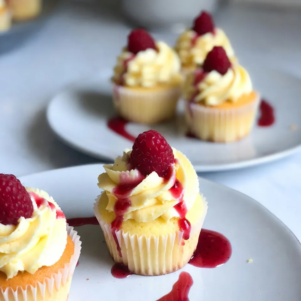To make Raspberry Lemonade Cupcakes, you will need: - 1 ½ cups all-purpose flour - 1 teaspoon baking powder - ½ teaspoon baking soda - ¼ teaspoon salt - ½ cup unsalted butter, softened - 1 cup granulated sugar - 2 large eggs, at room temperature - Zest of 1 lemon (about 1 tablespoon) - 1 teaspoon pure vanilla extract - ½ cup buttermilk, at room temperature - ½ cup fresh raspberries, plus extra for garnish - 1 tablespoon freshly squeezed lemon juice If you don’t have some ingredients, here are a few swaps you can use: - Use coconut oil instead of butter for a dairy-free option. - Substitute Greek yogurt for buttermilk to add extra creaminess. - If you lack fresh raspberries, you can try using blueberries or strawberries. - Lemon zest can be replaced with lime zest if you want a twist. Using fresh ingredients is key for flavor. Fresh raspberries taste sweeter and brighter. They add a juicy burst to each bite. Fresh lemons provide a zesty kick, enhancing the cupcake's flavor. Always choose ripe fruits for the best results. This ensures your cupcakes are vibrant and tasty. Fresh ingredients also contribute to better texture. You will notice the difference in every delightful bite. {{ingredient_image_2}} First, you need to preheat your oven to 350°F (175°C). This step is key for even baking. Next, grab a cupcake pan and line it with paper liners. This keeps the cupcakes from sticking and makes for easy serving. In a medium bowl, whisk together the all-purpose flour, baking powder, baking soda, and salt. Make sure they mix well. This mix gives the cupcakes their structure. After mixing, set this bowl aside for later. Take a large mixing bowl. Use an electric mixer on medium speed to cream ½ cup of softened unsalted butter and 1 cup of granulated sugar together. Mix for about 3-4 minutes. You want the mixture to be light and fluffy. This is where the magic begins! Now, add 2 large eggs to the butter-sugar blend. Add one egg at a time. Make sure each is fully mixed in before adding the next. Next, gently mix in the lemon zest and 1 teaspoon of pure vanilla extract. This adds a wonderful flavor. Gradually add the dry mixture into the wet mix. Alternate adding dry ingredients with ½ cup of buttermilk and 1 tablespoon of lemon juice. Start and end with the flour mix. Mix just until combined. Be careful not to overmix or the cupcakes may turn out dense. Now it's time to fold in the star of the show: the raspberries. Use a spatula to gently fold in ½ cup of fresh raspberries. Be careful not to crush them too much. You want them to keep their shape for bursts of flavor in every bite. Spoon the batter into the prepared liners, filling each about two-thirds full. This allows room for the cupcakes to rise. Bake them in the oven for 18-20 minutes. To check if they are done, insert a toothpick into the center of one. If it comes out clean, they are ready. Once baked, let them cool in the pan for about 5 minutes. Then, transfer them to a wire rack to cool completely. Enjoy the sweet smell wafting through your kitchen! To make light and fluffy cupcakes, start with room temperature butter and eggs. Cream the butter and sugar for 3-4 minutes until it's airy. This step adds air to your batter, making it rise nicely. Always mix gently when adding dry ingredients to keep the batter light. Overmixing can ruin your cupcakes. Mix the batter just until combined. If you see dry spots, that’s okay. This helps keep your cupcakes soft. Remember, a few lumps are fine! When you add raspberries, be gentle. Use a spatula to fold them in. This keeps the berries whole and juicy. Avoid smashing them, as this can turn your batter pink. You want to see lovely bits of raspberry in each bite. Let your cupcakes cool completely before frosting. If you frost them too soon, the frosting will melt. Place them on a wire rack for even cooling. This way, your frosting stays fluffy and beautiful. Pro Tips Use Room Temperature Ingredients: Ensure that your butter, eggs, and buttermilk are at room temperature before mixing. This helps create a smoother batter and contributes to a lighter cupcake texture. Be Gentle with the Raspberries: When folding in the raspberries, use a light hand to avoid crushing them. This preserves their shape and adds beautiful bursts of color and flavor to each cupcake. Check for Doneness: To ensure your cupcakes are perfectly baked, insert a toothpick into the center. If it comes out clean or with a few crumbs, they are done; if it comes out wet, give them a few more minutes in the oven. Cool Completely Before Frosting: Let the cupcakes cool completely on a wire rack before frosting them. This prevents the frosting from melting and helps maintain the beautiful presentation. {{image_4}} When it comes to frosting, you have fun options. You can use lemon buttercream for a bright, zesty taste. Cream cheese frosting also works well, adding a rich, tangy flavor. Just mix cream cheese with butter, sugar, and lemon juice. Spread it on top for a creamy finish. You can even add a sprinkle of lemon zest for more zing. Raspberries shine in these cupcakes, but feel free to swap them out. Strawberries bring a sweet touch. Chop them into small pieces and fold them in gently. Blueberries are another great choice. They add a burst of color and flavor. You can even mix fruits for a fun surprise in every bite! Want to make these cupcakes gluten-free? It’s easy! Replace all-purpose flour with a gluten-free blend. Make sure it has xanthan gum to help with texture. Check your baking powder, too; some brands are gluten-free. This way, everyone can enjoy these tasty treats without worry. Store your Raspberry Lemonade Cupcakes in an airtight container. This keeps them fresh. Place the container at room temperature for up to three days. If you want them to last longer, refrigerate them. Just let them come back to room temperature before serving. To freeze your cupcakes, wait until they cool completely. Wrap each cupcake in plastic wrap. Then, place them in a freezer-safe bag or container. They will stay fresh for up to three months. When you’re ready to enjoy them, take out what you need. Let them thaw in the fridge overnight or at room temperature for a few hours. These cupcakes taste best within three days if stored at room temperature. In the fridge, they can last up to a week. If frozen, they remain good for three months. Always check for any signs of spoilage before eating! Yes, you can use frozen raspberries. Just thaw them first. Drain any excess juice to avoid soggy cupcakes. Gently fold them into the batter, treating them carefully. This way, they won't break down too much. To prevent sticking, use high-quality paper liners. Lightly spray them with cooking oil before adding the batter. Allow the cupcakes to cool in the pan for a few minutes before transferring them to a wire rack. This helps them release easily. If you don't have buttermilk, you can make a quick substitute. Mix ½ cup of milk with 1 tablespoon of lemon juice or vinegar. Let it sit for about 5 minutes. This will mimic the acidity of buttermilk and keep your cupcakes moist. To add more tartness, increase the lemon juice to 2 tablespoons. You can also add more lemon zest for an extra kick. Consider using a tart raspberry jam as a filling. This will enhance the tangy flavor in each bite. Yes, you can make a cake. Simply pour the batter into a greased cake pan. Bake at 350°F (175°C) for 25-30 minutes. Check with a toothpick to ensure it’s done. Frost the cake with the same lemon buttercream for a lovely finish. In this post, we covered the key ingredients and steps for making Raspberry Lemonade Cupcakes. You learned about ingredient swaps and the need for fresh items. We outlined easy steps, from mixing to baking. I shared tips for fluffiness and frosting options. You also found storage methods for lasting enjoyment. Remember, great cupcakes start with good ingredients. Enjoy baking and have fun with flavors!